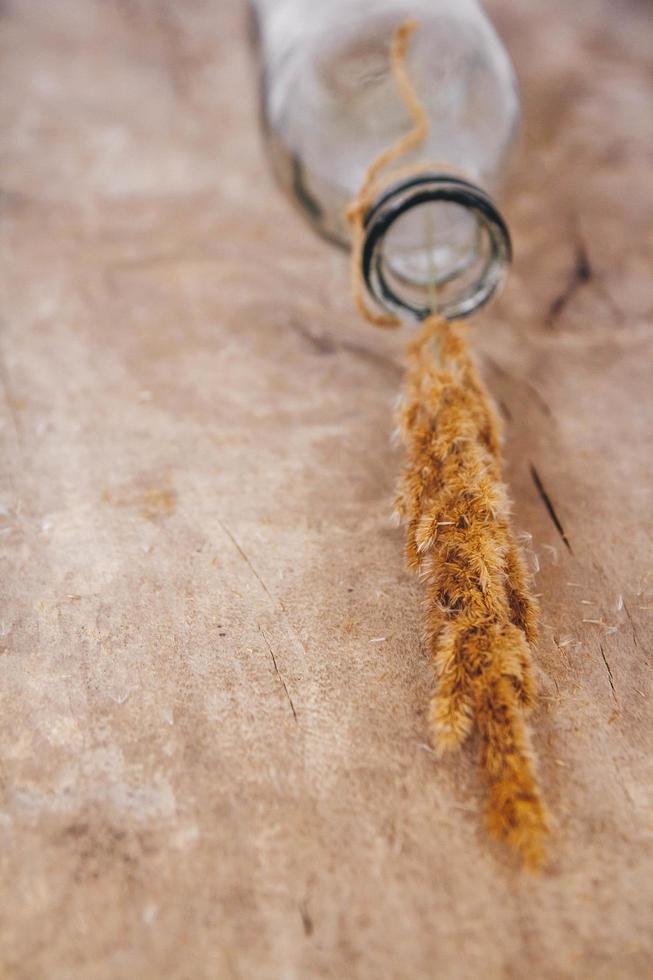 Still life of a bouquet of dried flowers in a glass bottle on a wooden table. Place for text or advertising photo