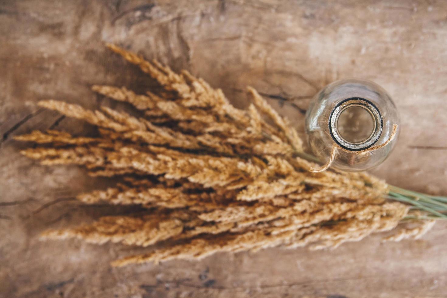 Still life of a bouquet of dried flowers in a glass bottle on a wooden table. Place for text or advertising photo