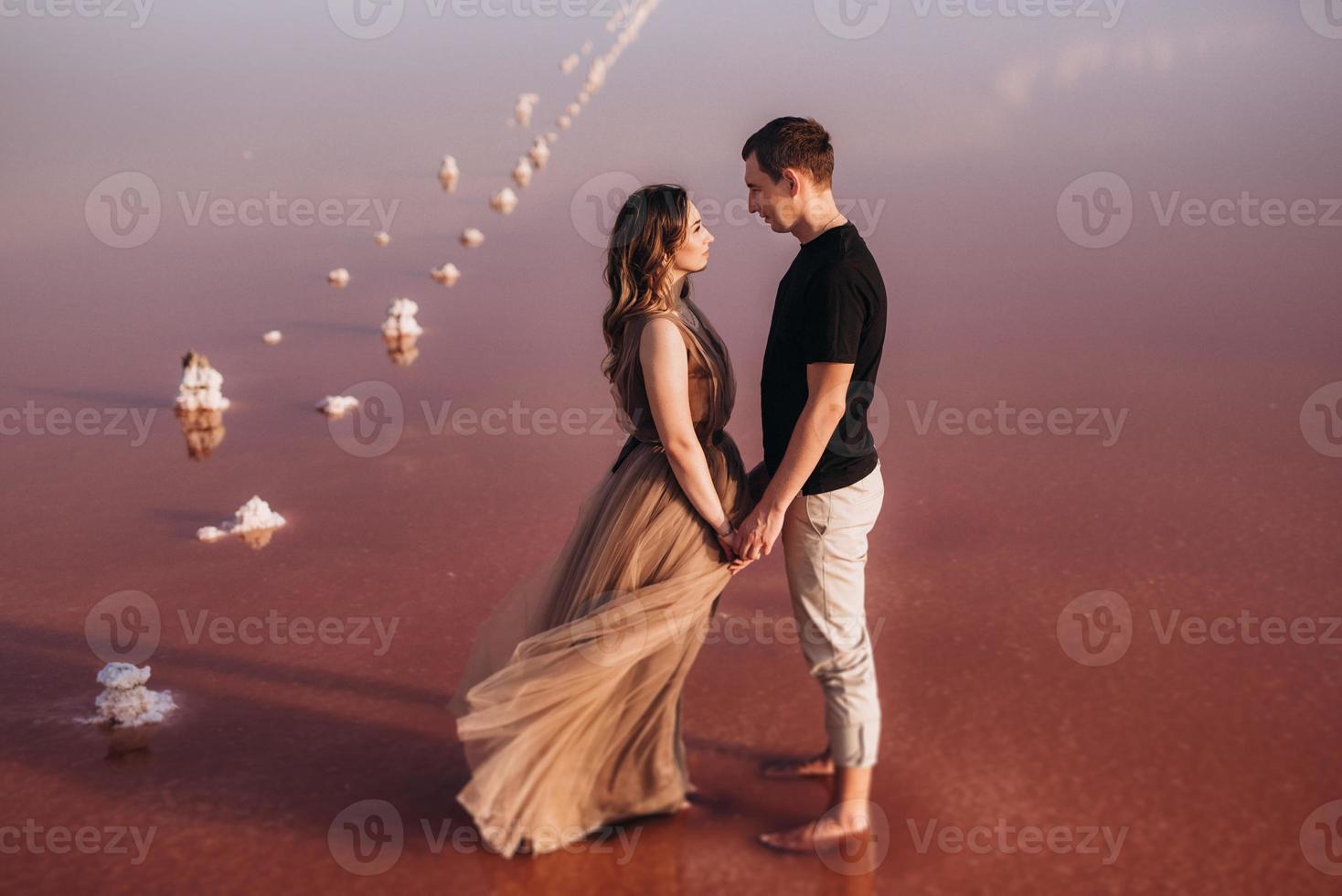 girl and a guy on the shore of a pink salt lake photo