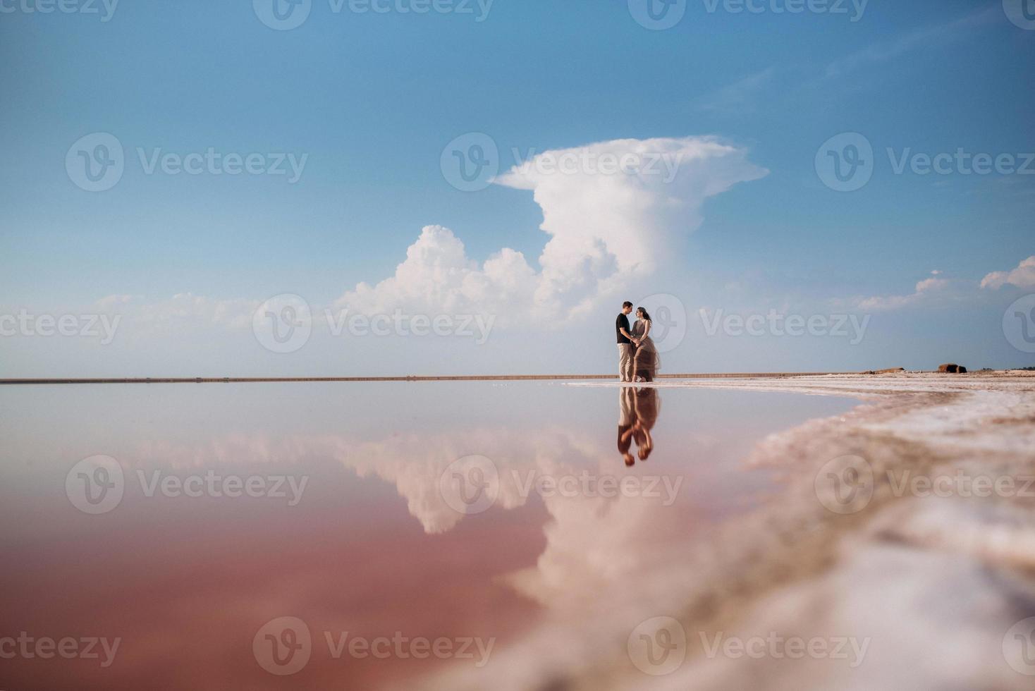 girl and a guy on the shore of a pink salt lake photo