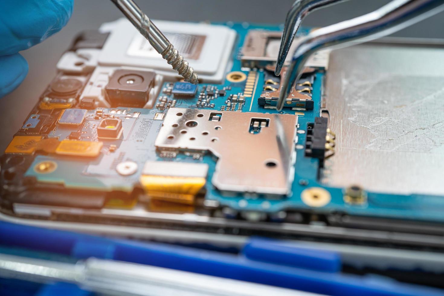 Technician repairing inside of mobile phone by soldering iron. Integrated Circuit. the concept of data, hardware, technology. photo