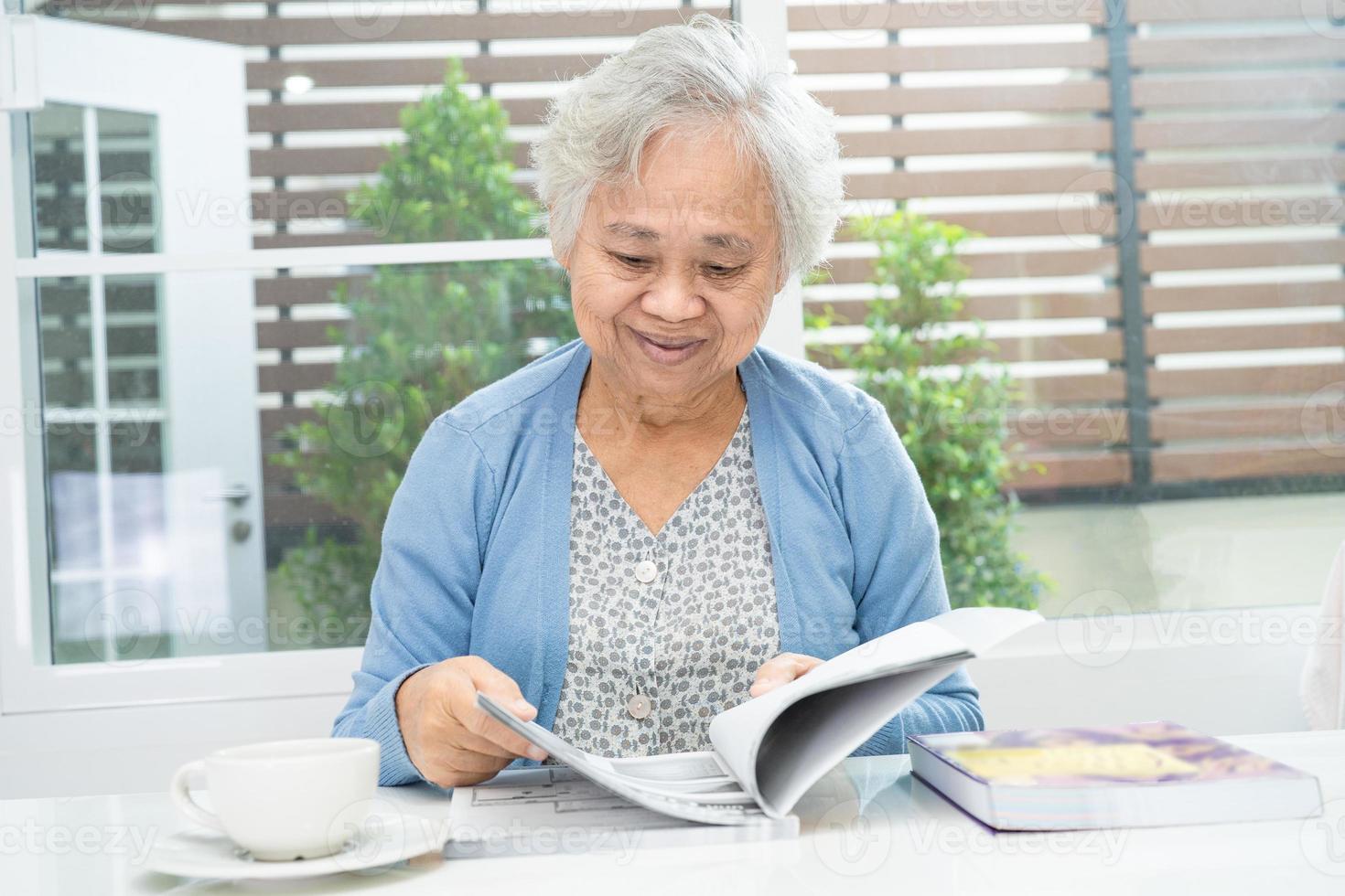 Asian senior or elderly old lady woman reading a book for practice brain while living at home, resting hobby retirement concept. photo