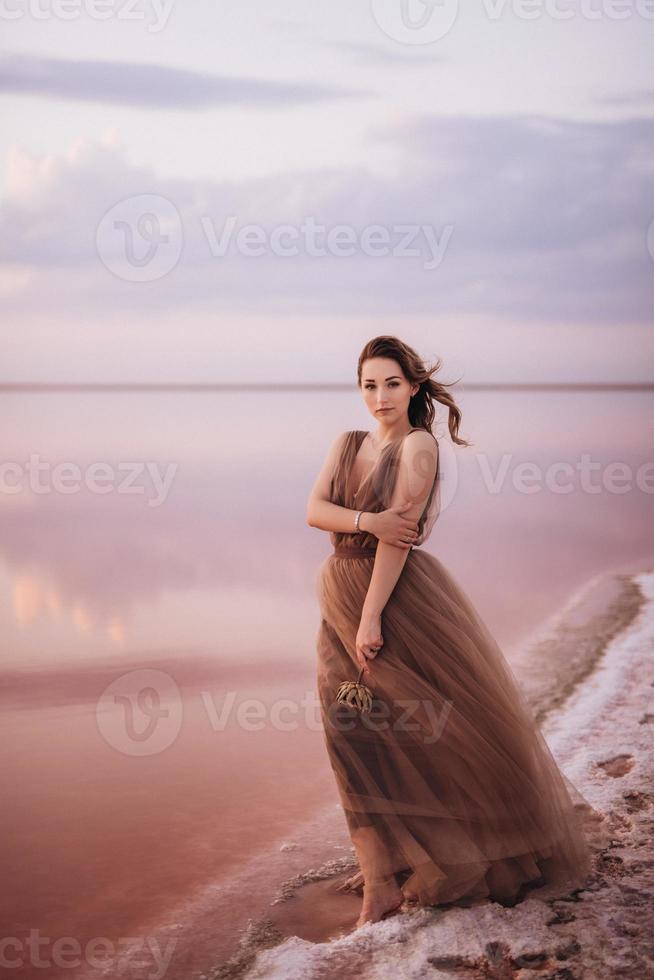 niña en la orilla de un lago salado rosa foto