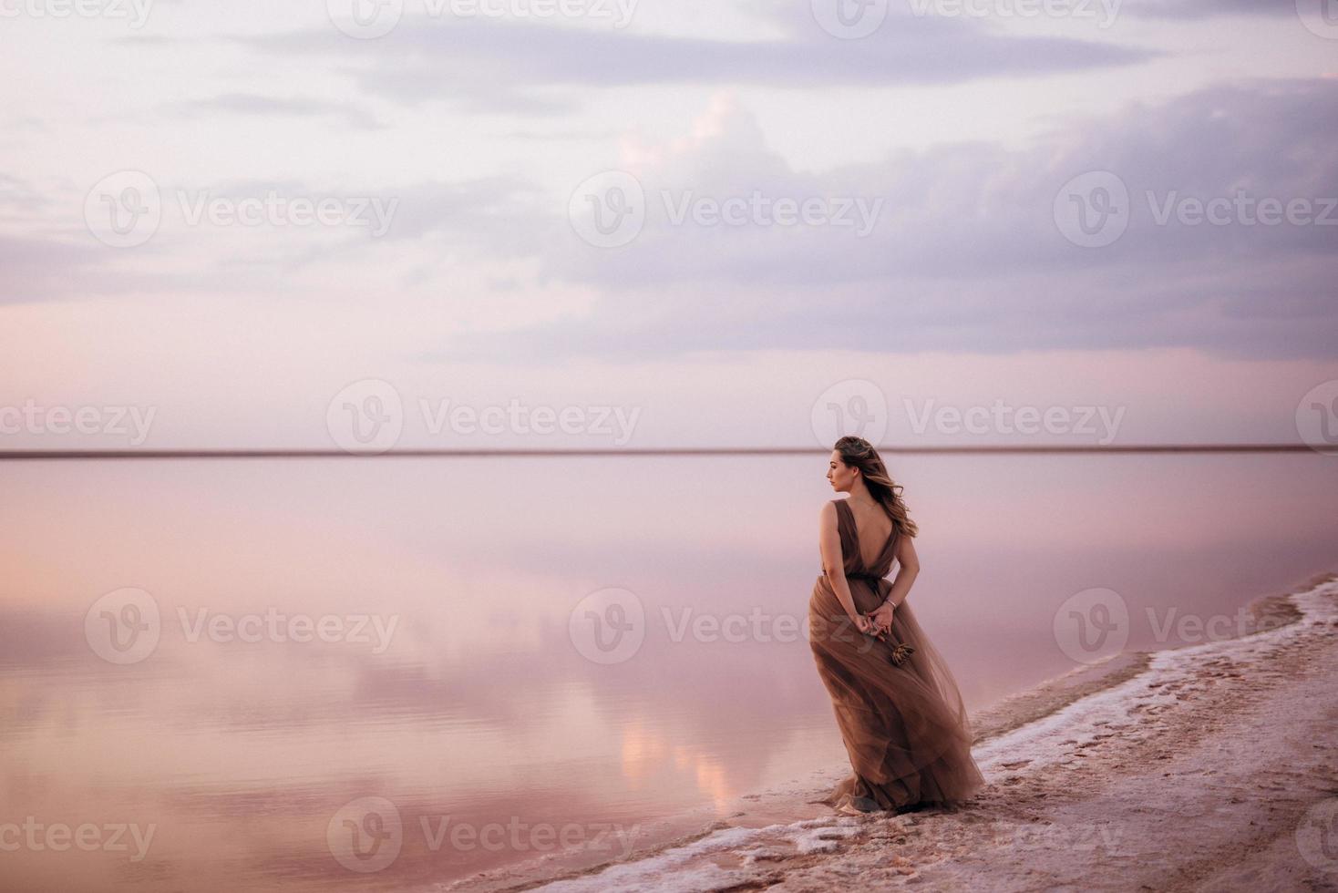 niña en la orilla de un lago salado rosa foto