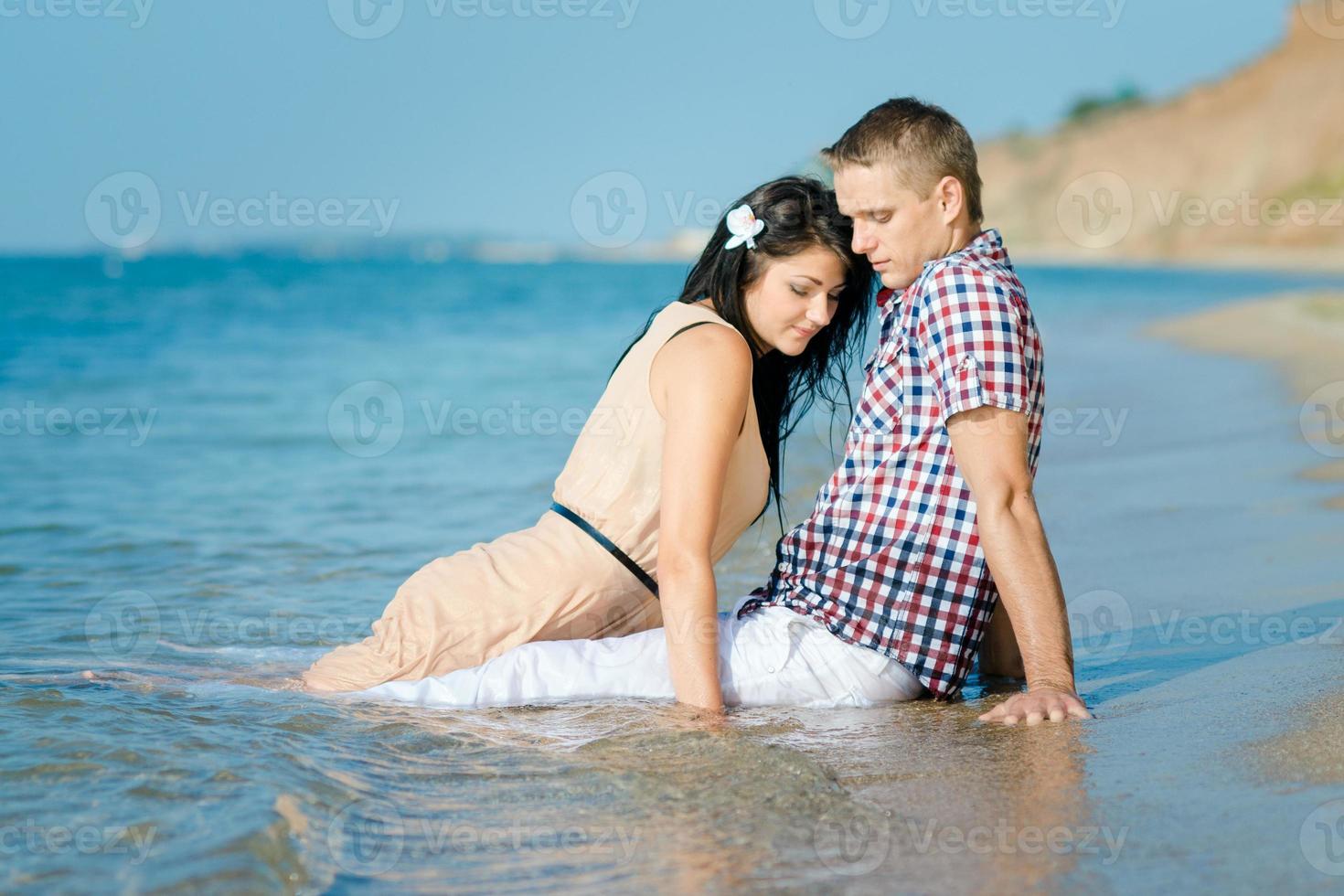 un chico y una chica caminan por la orilla del mar foto