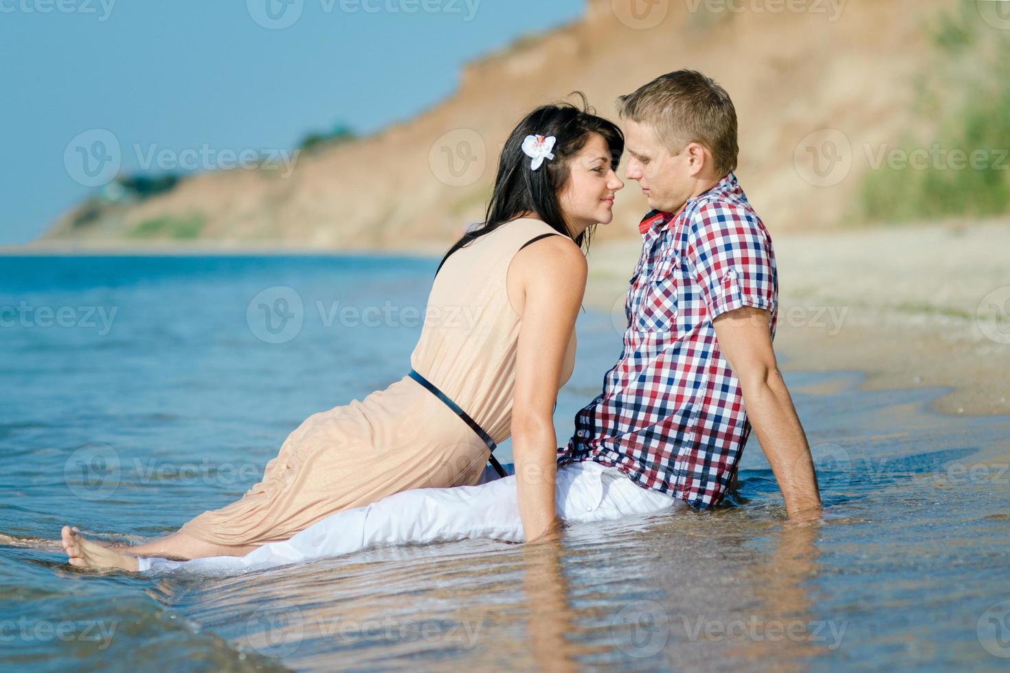 un chico y una chica caminan por la orilla del mar foto