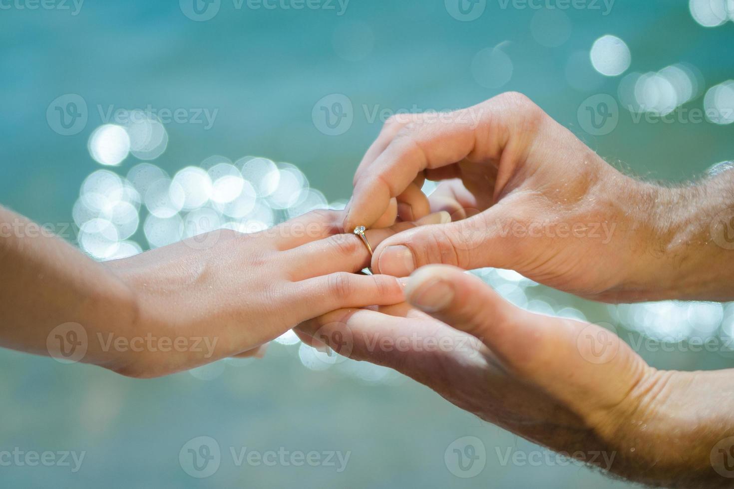 La mano del chico pone un anillo de bodas en la de una chica. foto