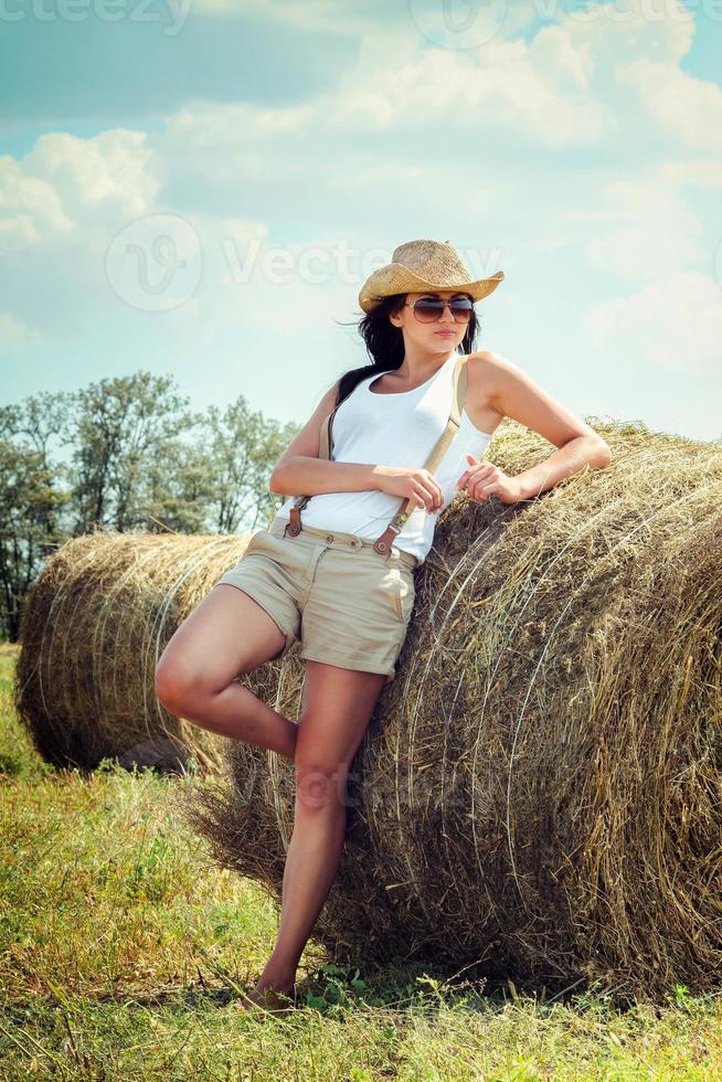 girl with black hair in beige wool coats stands near the haystacks photo