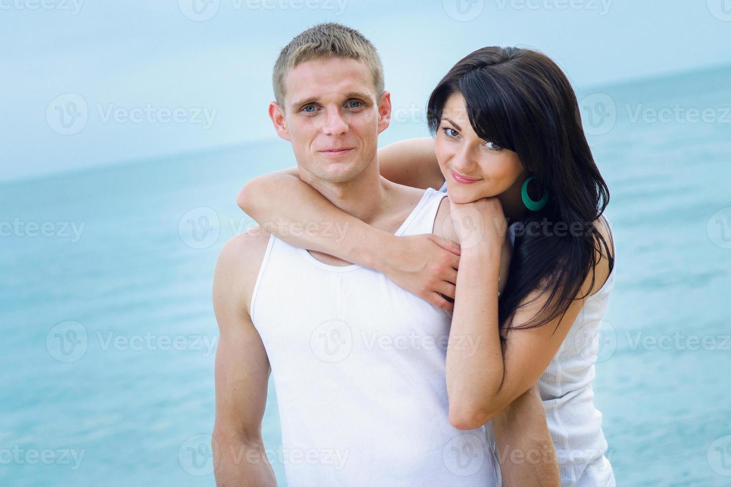 chico y una chica en jeans y camisetas blancas en la playa foto