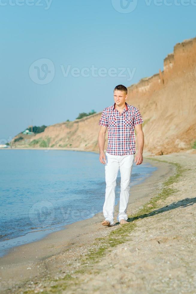 guy in white trousers walks along the seashore against photo