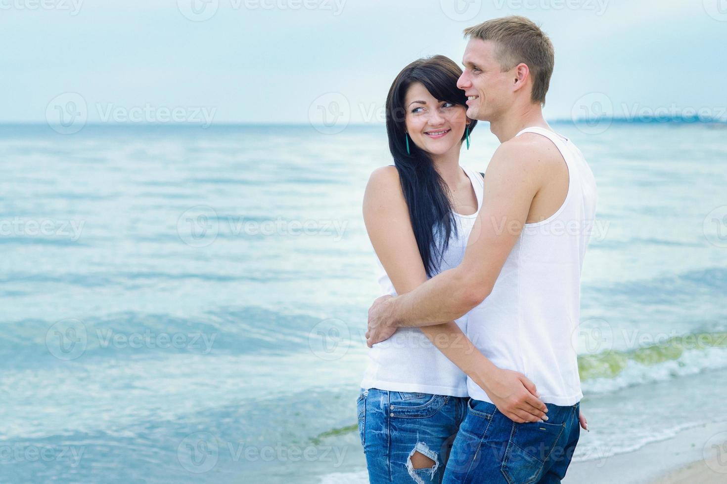 chico y una chica en jeans y camisetas blancas en la playa foto