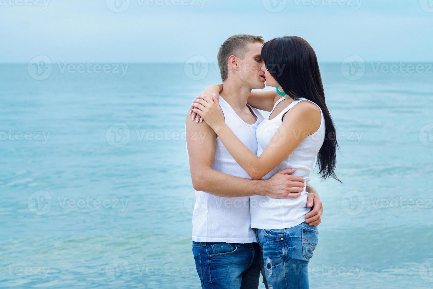 chico y una chica en jeans y camisetas blancas en la playa foto