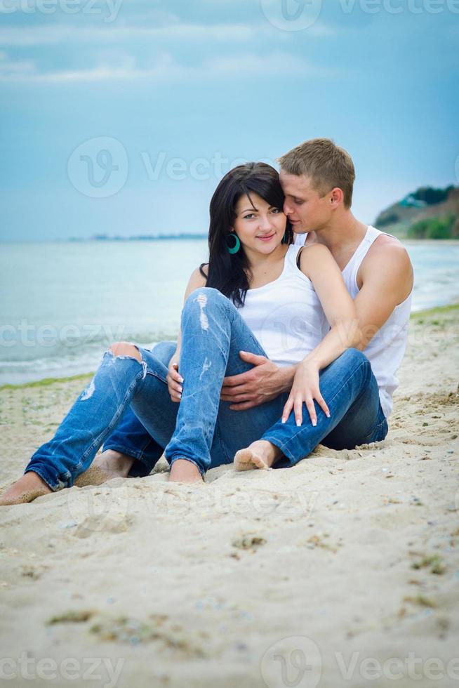 guy and a girl in jeans and white t-shirts on the beach photo