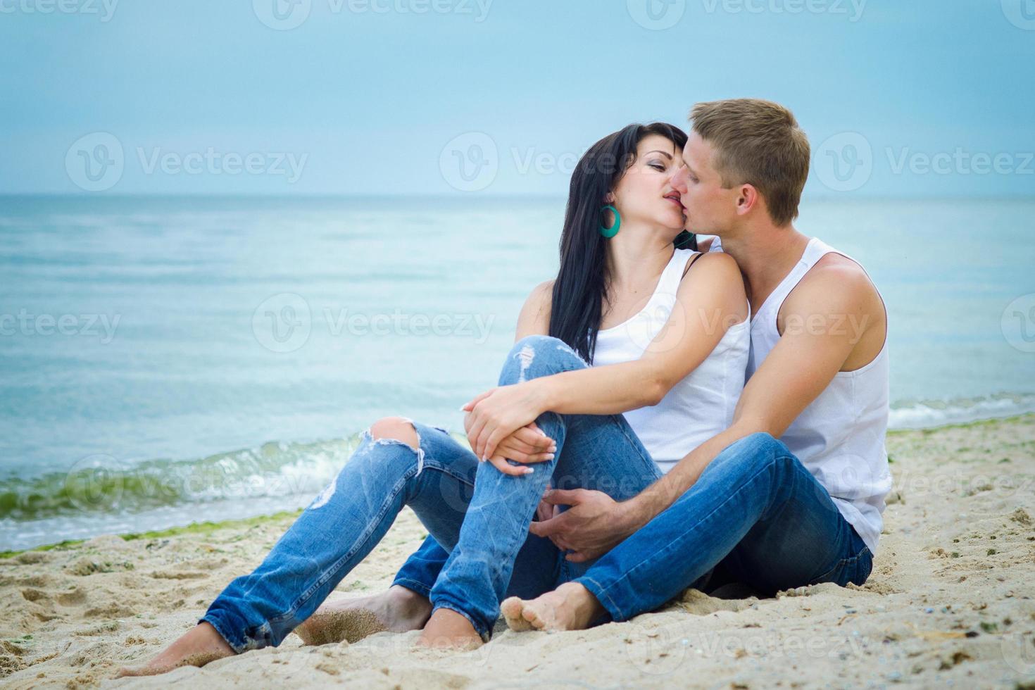 chico y una chica en jeans y camisetas blancas en la playa foto