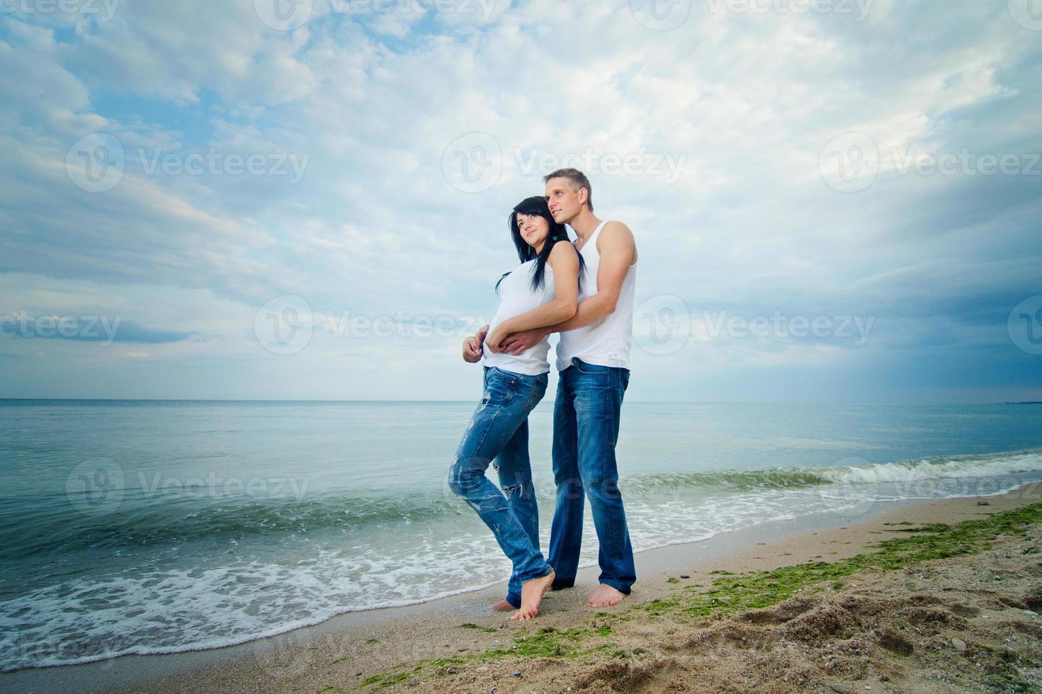 guy and a girl in jeans and white t-shirts on the beach photo