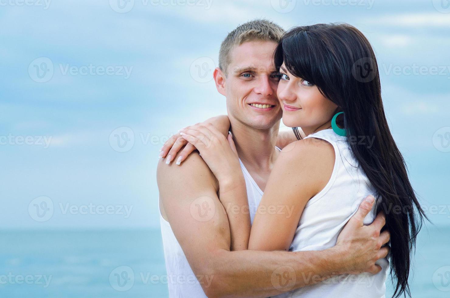 guy and a girl in jeans and white t-shirts on the beach photo