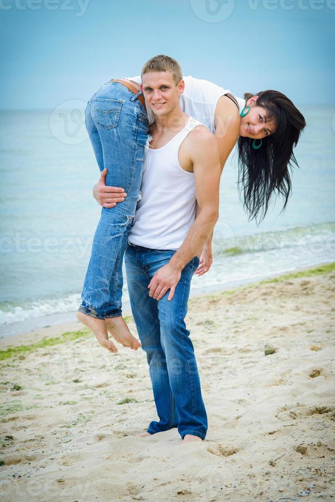 chico y una chica en jeans y camisetas blancas en la playa foto