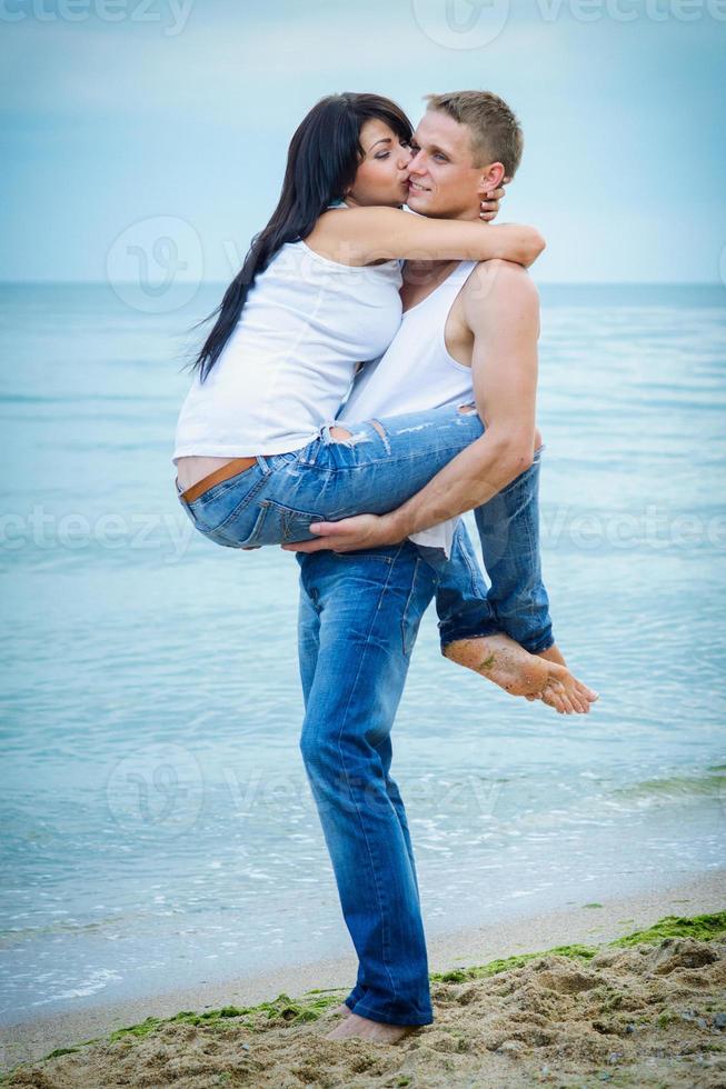 chico y una chica en jeans y camisetas blancas en la playa foto