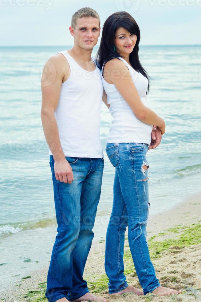 guy and a girl in jeans and white t-shirts on the beach photo