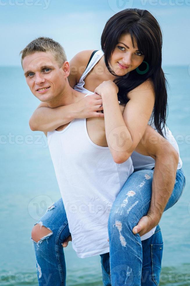 chico y una chica en jeans y camisetas blancas en la playa foto