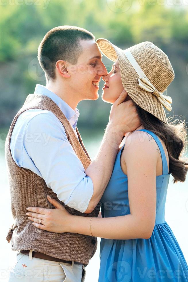 una pareja joven, un chico y una chica caminan cerca de un lago de montaña rodeado foto