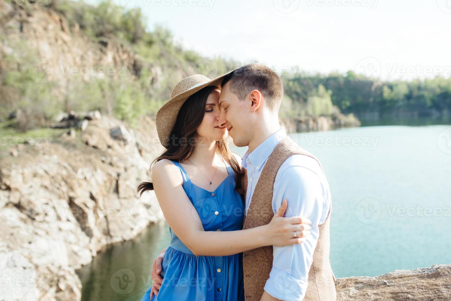 a young couple a guy and a girl are walking near a mountain lake surrounded photo