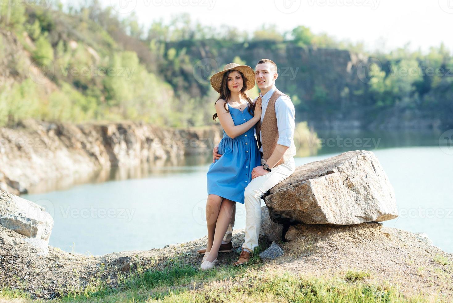 una pareja joven, un chico y una chica caminan cerca de un lago de montaña rodeado foto