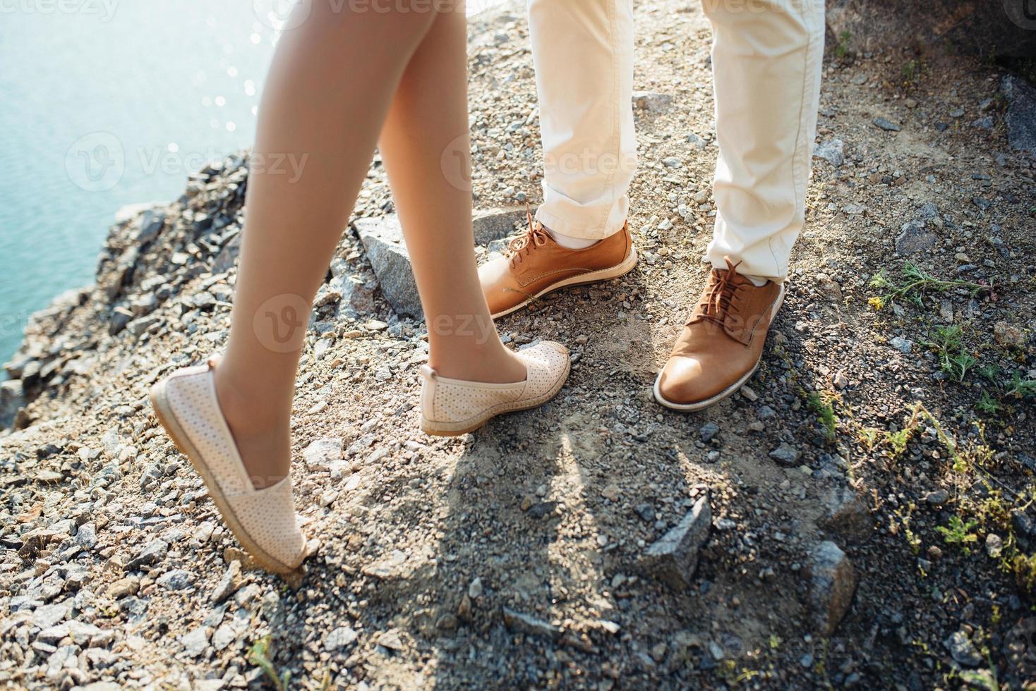 una pareja joven, un chico y una chica caminan cerca de un lago de montaña rodeado foto