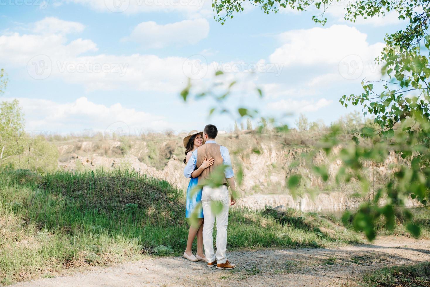 a young couple a guy and a girl are walking near a mountain lake surrounded photo