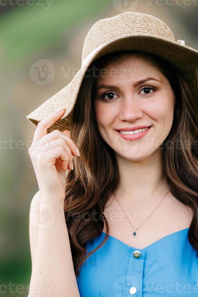 Chica joven con un sombrero de paja con ala grande en las laderas de las montañas foto