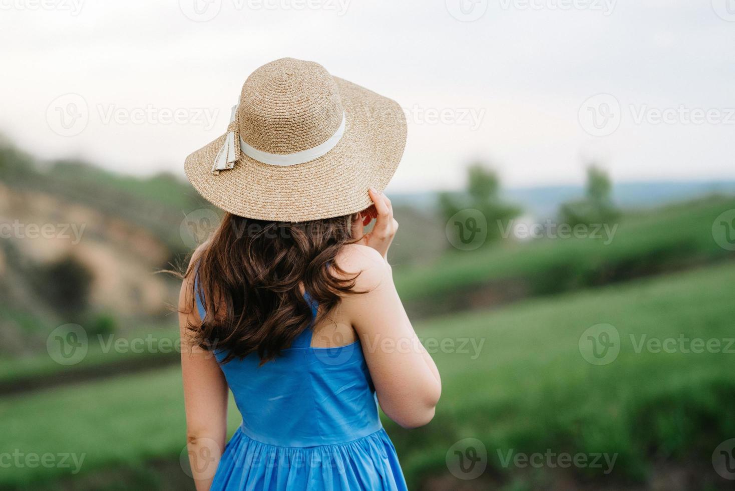 Chica joven con un sombrero de paja con ala grande en las laderas de las montañas foto