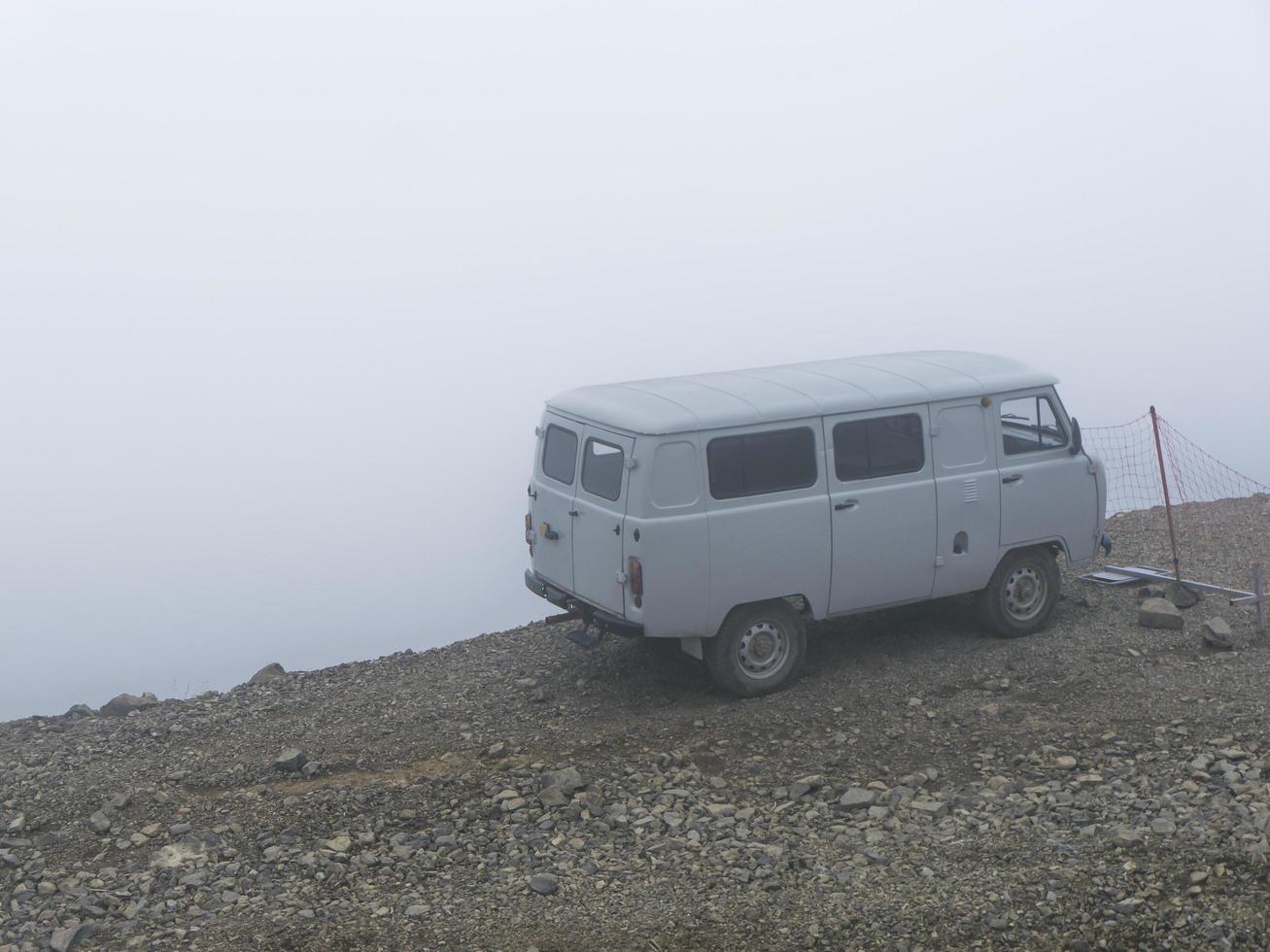 coche al borde de un abismo en la niebla de las nubes. montañas del cáucaso foto