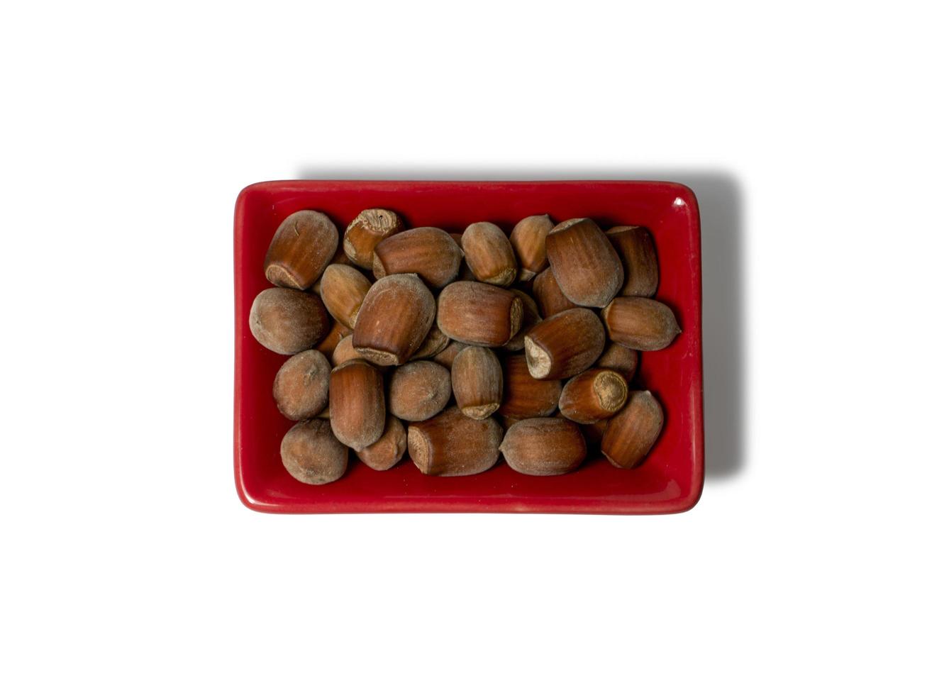 Hazelnuts in a red rectangular saucer isolated on white background. View from above photo
