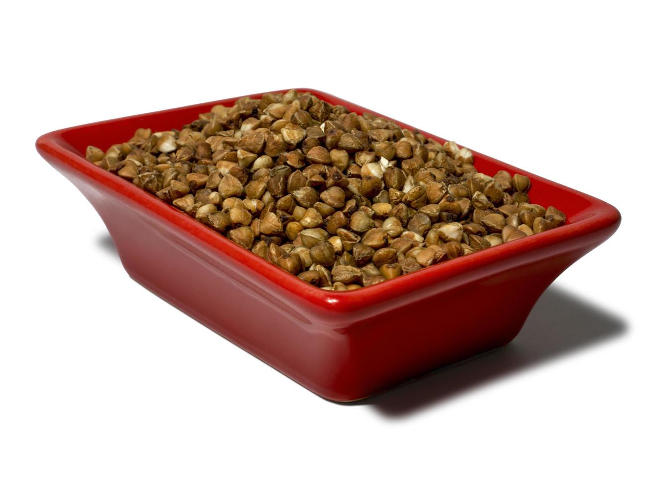 Buckwheat in a red rectangular saucer isolated on white background. Close-up photo
