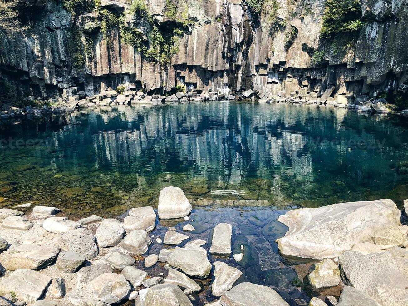 roca reflejada en el agua. lava solidificada cerca del agua de un lago en la isla de jeju. Corea del Sur foto