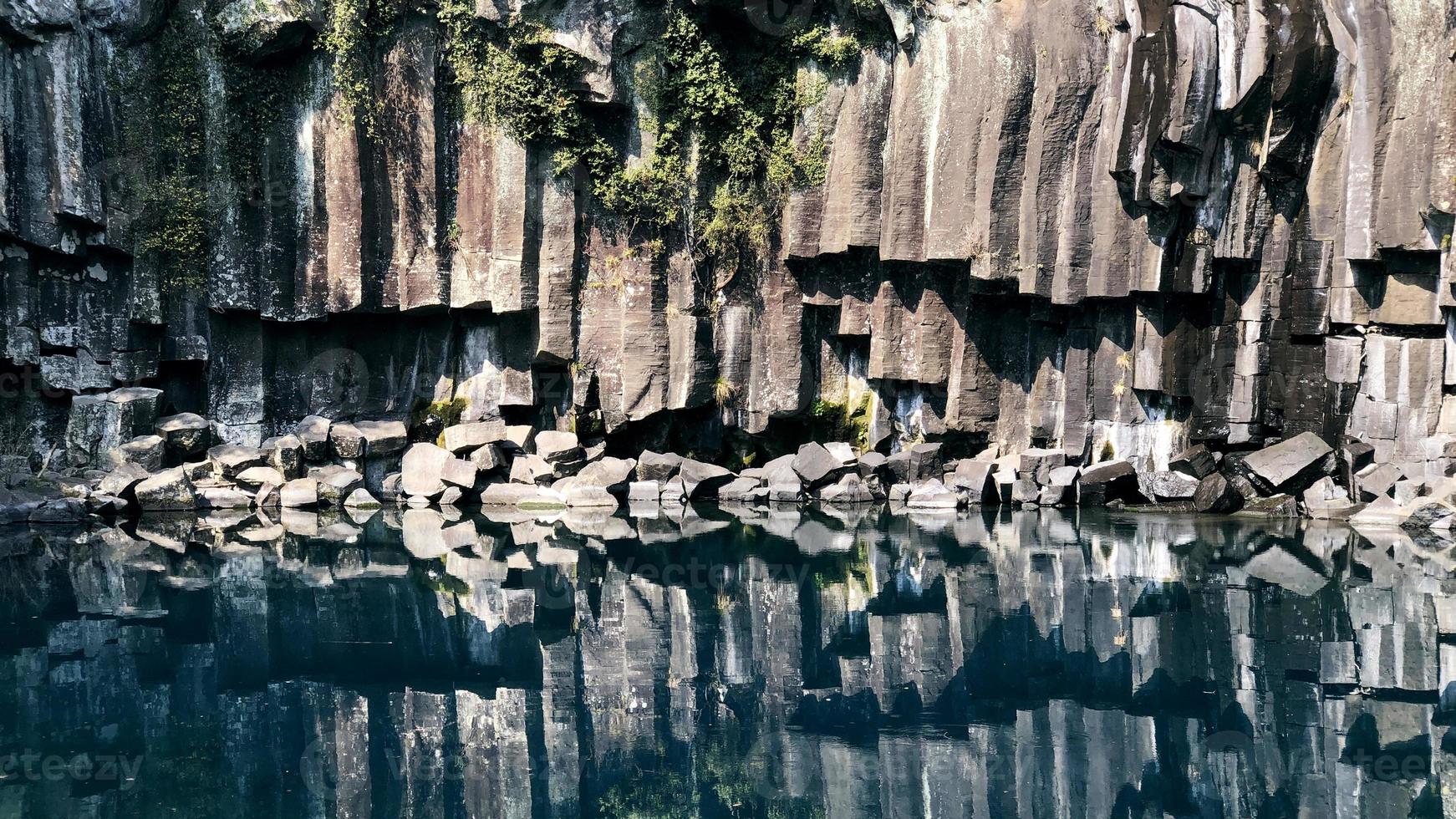 Rock reflected in water. Solidified lava near water of a lake in Jeju island. South Korea photo
