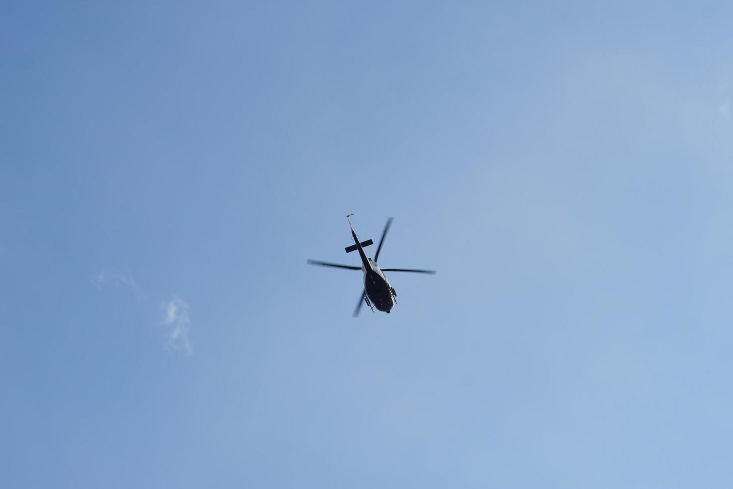 On the azure sky, a helicopter flies. photo