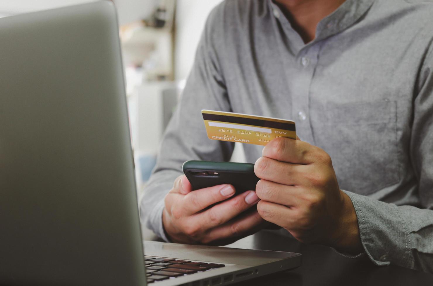 Hombre que sostiene transacciones financieras con tarjeta de crédito o compras en línea, utilizando marketing en línea por computadora. foto