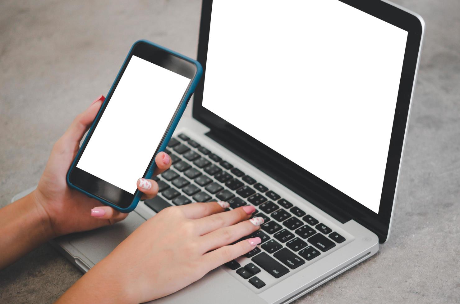 mano que sostiene la imagen de la maqueta del teléfono computadora portátil con pantalla en blanco para texto publicitario en el escritorio del lugar de trabajo en la oficina. foto
