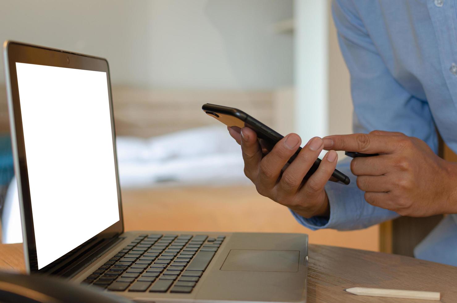 Hombre con teléfono inteligente móvil y computadora portátil en el escritorio foto