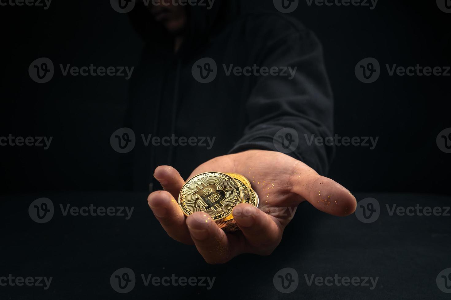 un bitcoin dorado en la mano de un hombre misterioso. foto