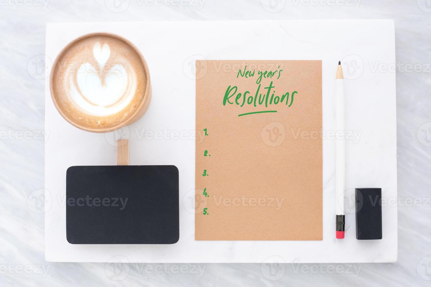 Top view of new year's resolution, pencil, eraser notepad and coffee cup on marble and stack on marble table photo