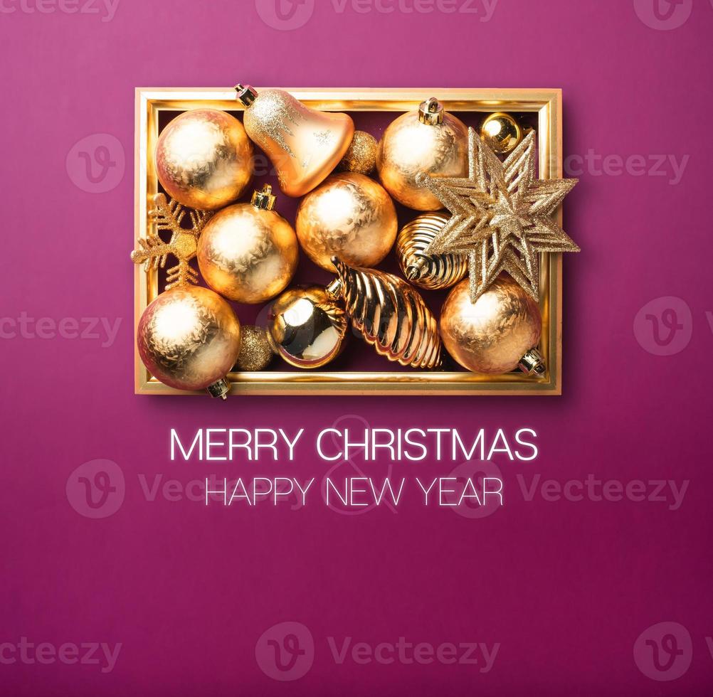 Merry Christmas and happy new year.Shiny gold Christmas decoration ball and star with golden frame in purple photo