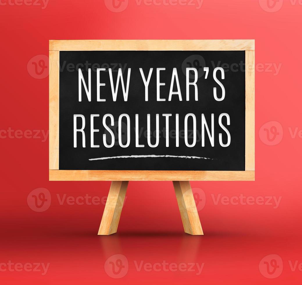 New year's resolutions word on Blackboard with easel on vivid red photo