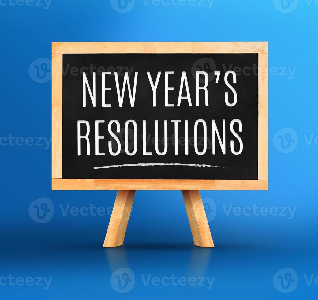 New year's resolutions word on Blackboard with easel on vivid blue photo