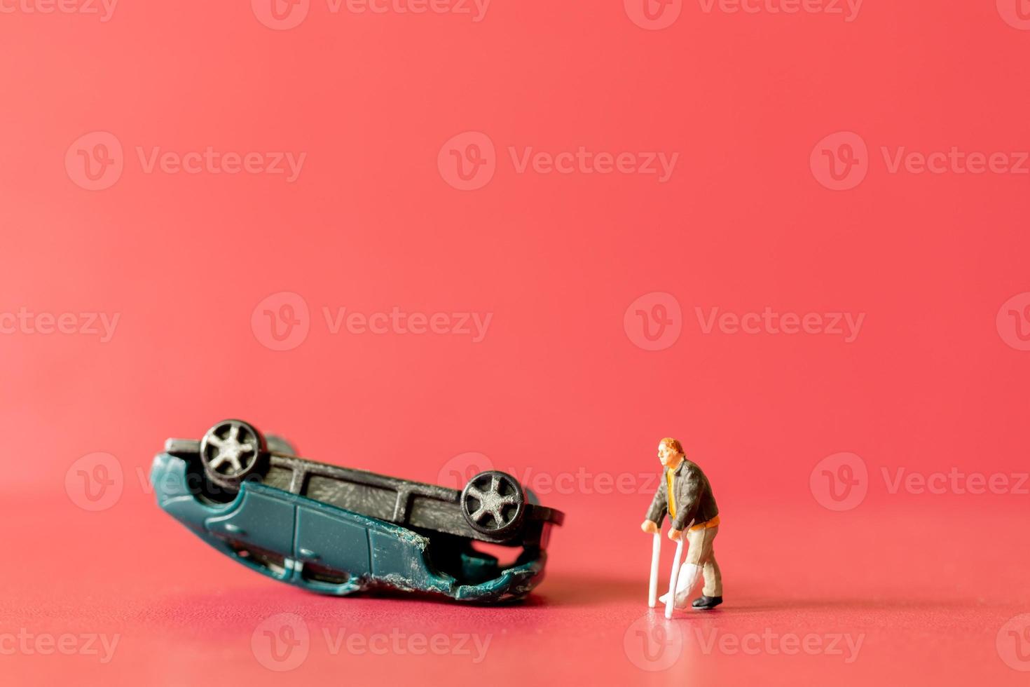 Miniature people broken leg man patient with bandage walking with crutch with toy car wreck photo