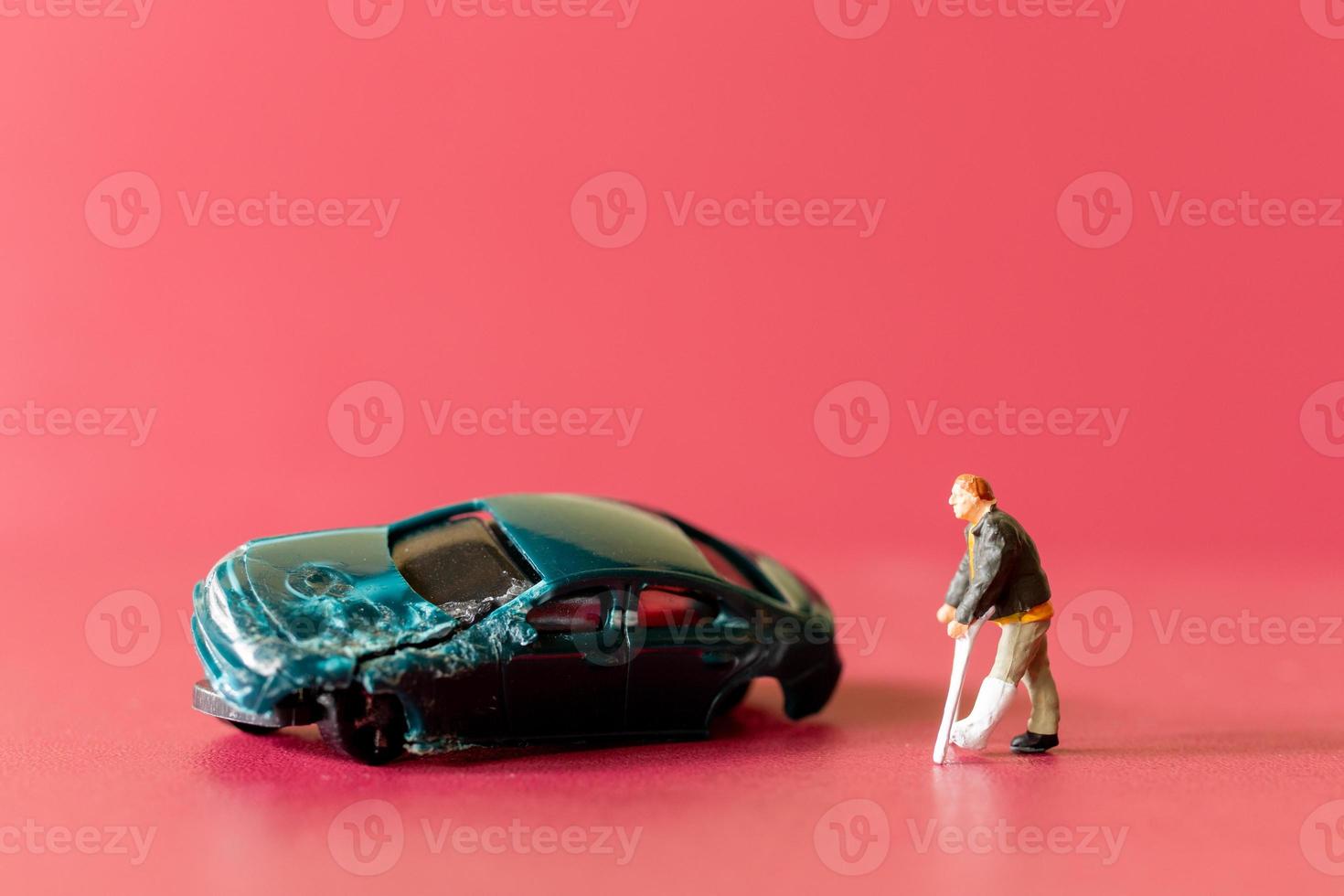 Miniature people broken leg man patient with bandage walking with crutch with toy car wreck photo