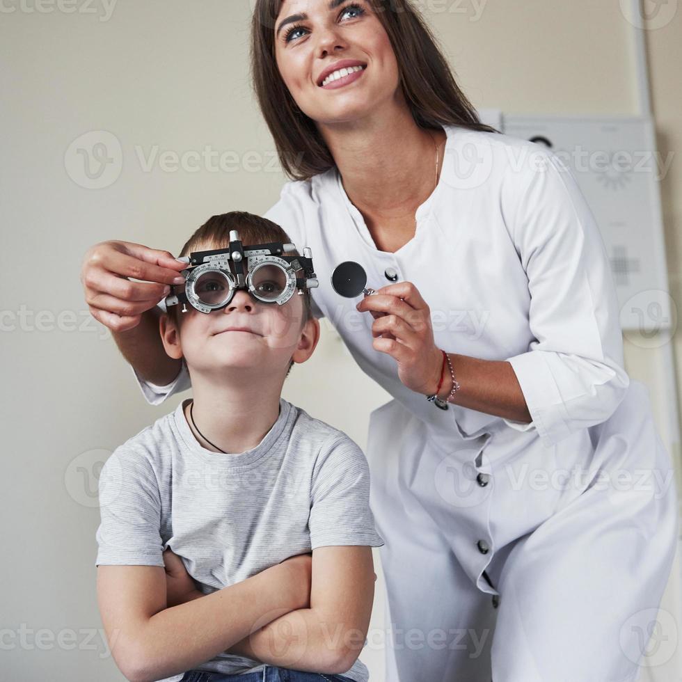 Can you see what is written there. Doctor tuning the phoropter to to determine visual acuity of the little boy photo