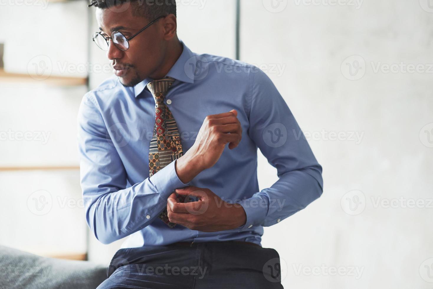 It will be busy day. Photo of black stylish man getting wearing clothes and preparing for the work