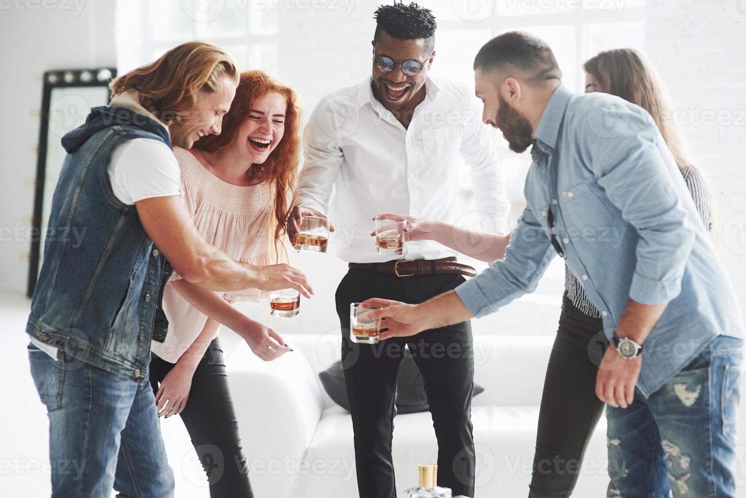 celebración del éxito del equipo. compañeros de equipo bebiendo whisky y riendo por un trato exitoso foto